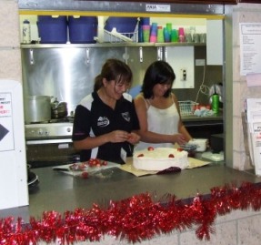 *Not too much fruit, thanks! We're not vegetarians! Tien Ha (left) and Victoria Tran start decorating the pavlova in the famous Moonee Valley canteen with non-meat products.